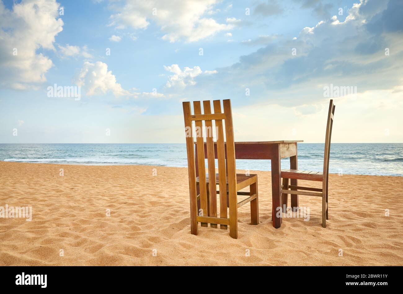 Holztisch und zwei Stühle am Strand. Stockfoto