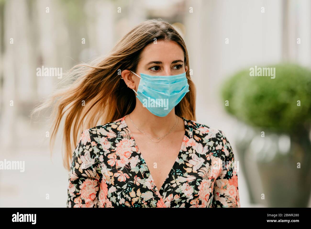 Mädchen, das während des Coronavirus eine Straße in spanien mit medizinischer Maske entlang geht Stockfoto