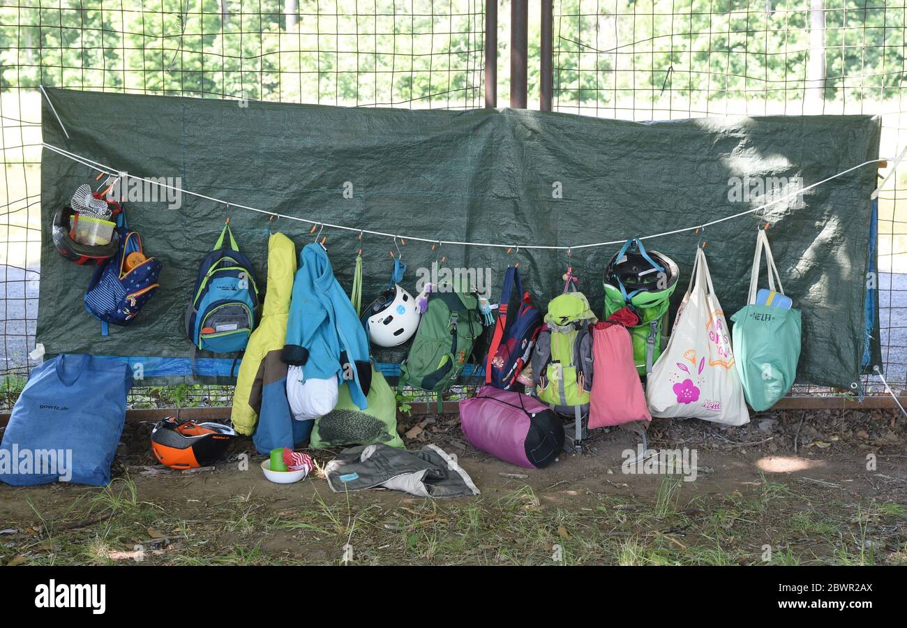 02. Juni 2020, Sachsen, Leipzig: Taschen, Taschen und Kleidung der Kinder des Leipziger BuchKindergartens hängen an einem Zaun auf der Galopprennbahn Scheibenholz. Seit einigen Tagen ist ein Zeltdorf auf der Rennbahn ihr Spielzimmer im Grünen für vier von fünf Kindergartengruppen. Aufgrund von Corona und dem begrenzten Regelbetrieb ist die Pflegezeit den ganzen Tag über unter Einhaltung der Hygienevorschriften und ausreichend Abstand zu den aufgesetzten Zelten und Spielplätzen gesichert. ACHTUNG: Redaktionelle Verwendung nur mit dem Namen 'BuchKindergarten'. Foto: Waltraud Grubitzsch/dpa-Zentralbil Stockfoto