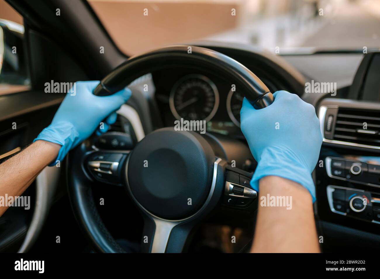 Ein Autofahrer legt während einer Epidemie eine medizinische Maske an, ein Taxifahrer in einer Maske, Schutz vor dem Virus. Fahrer im weißen Auto. Coronavirus, d Stockfoto
