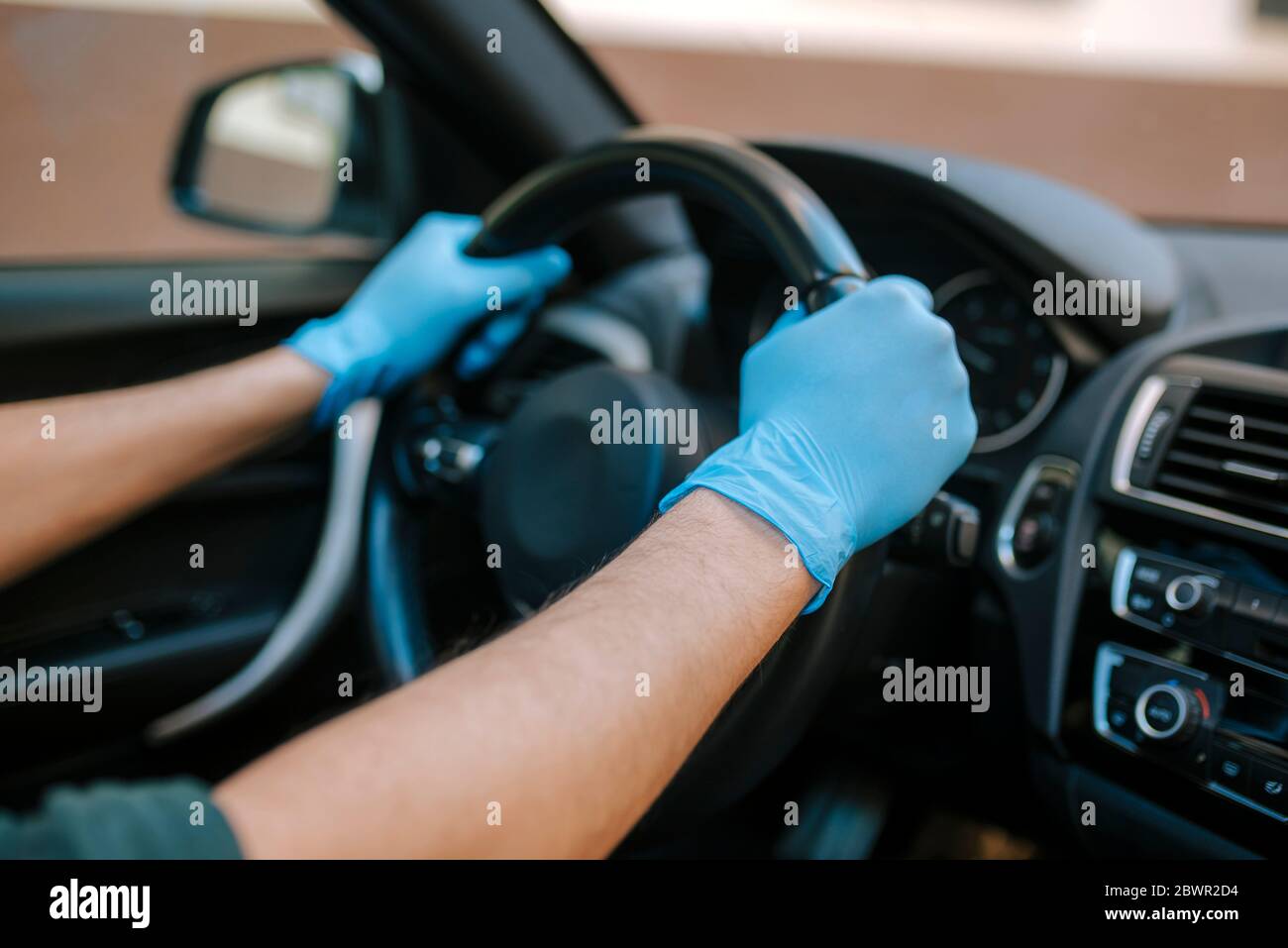 Ein Autofahrer legt während einer Epidemie eine medizinische Maske an, ein Taxifahrer in einer Maske, Schutz vor dem Virus. Fahrer im weißen Auto. Coronavirus, d Stockfoto