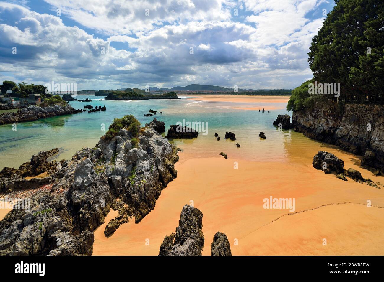 Felsformationen und sauberer nasser Sand am wunderschönen Strand bei Ebbe Stockfoto