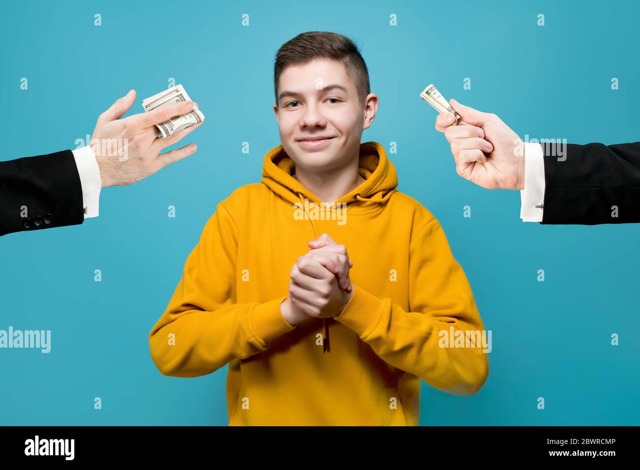 Ein junger Mann in einem hellen Sweatshirt freut sich, dass ein Geschäftsmann gibt ihm Geld Stockfoto