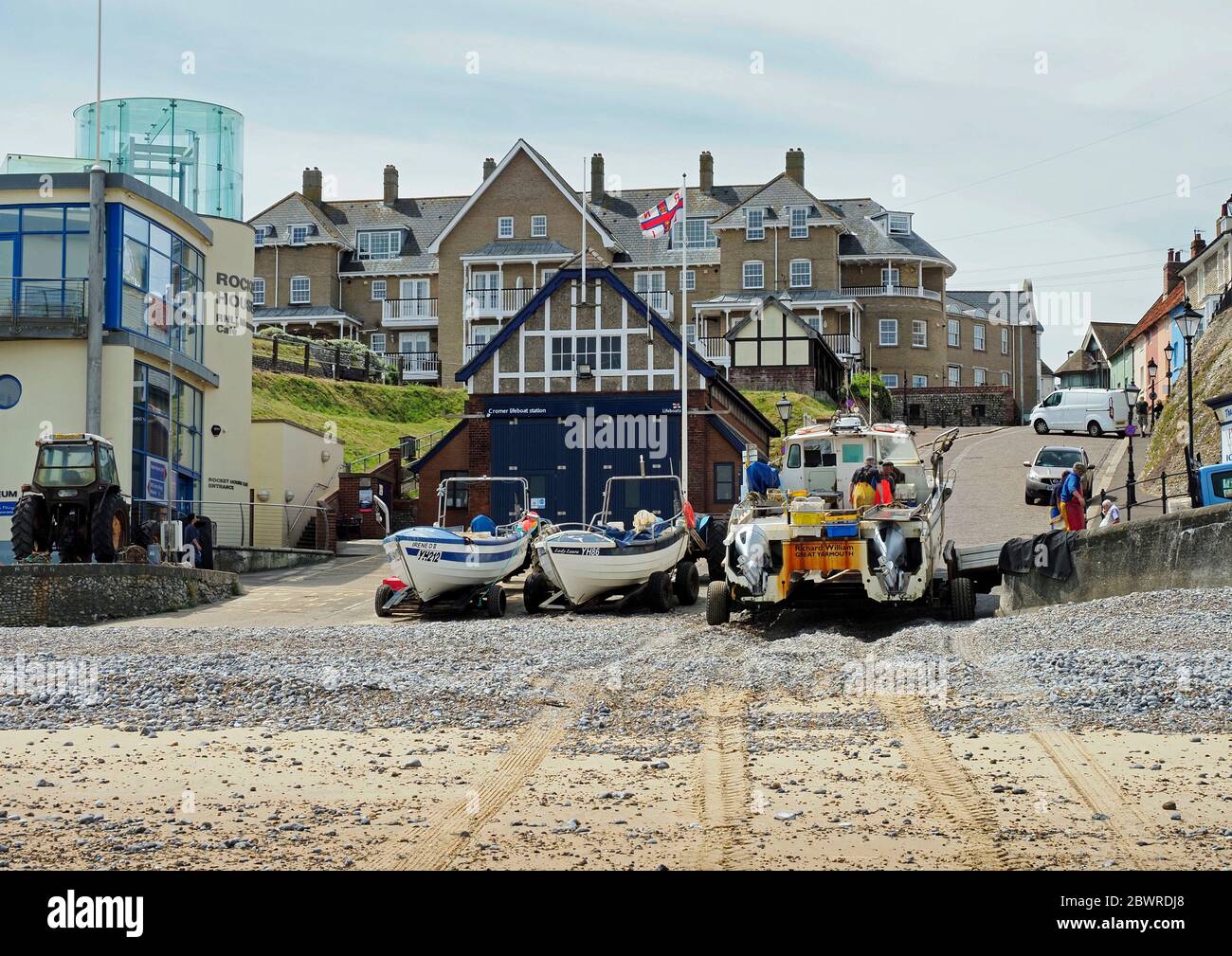Krabbenboote zogen am Strand unterhalb des Gangway in Cromer, Norfolk mit einem Boot aus, das den Fang des Morgens ausladende. Stockfoto
