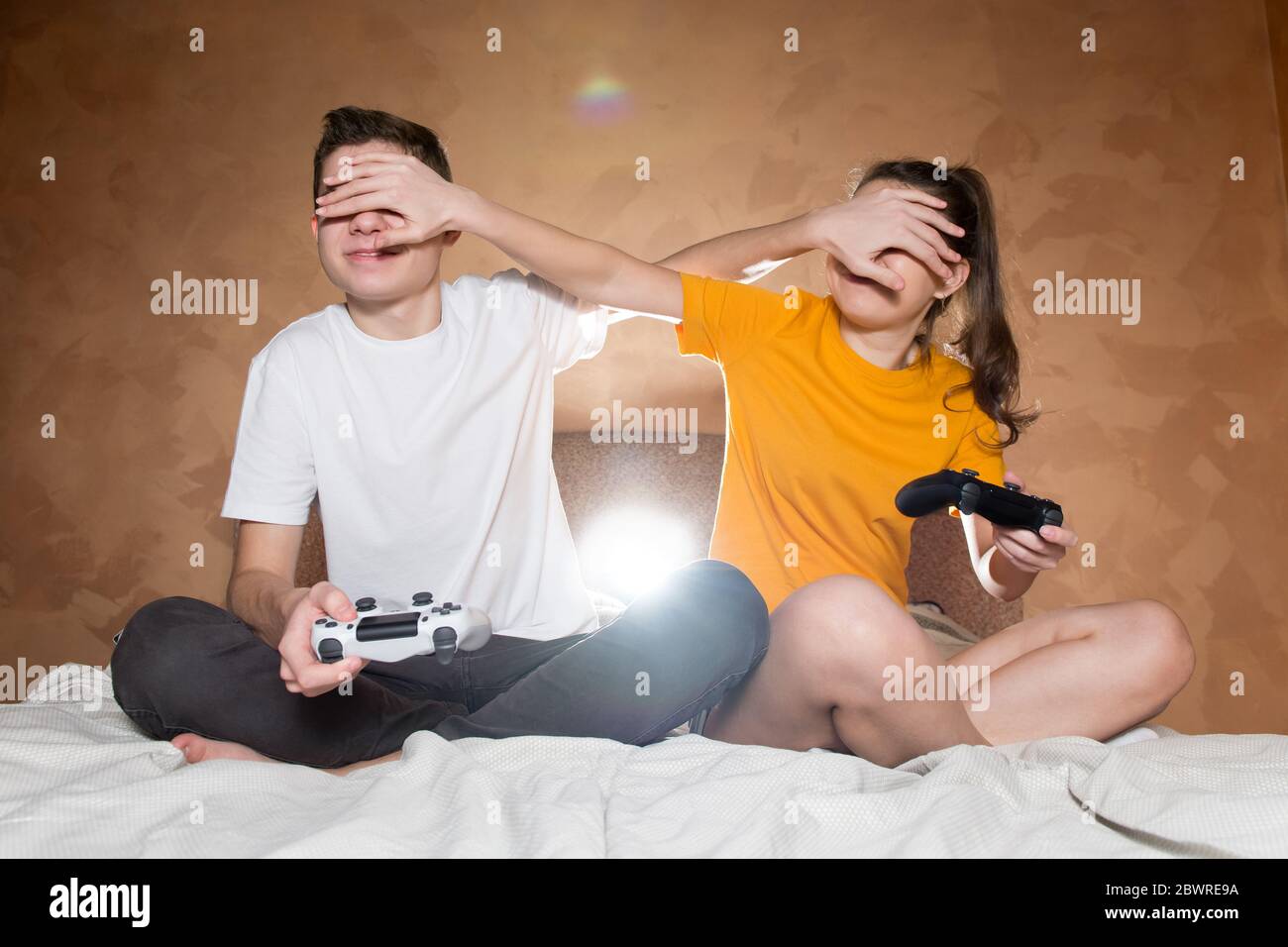 Ein Kerl mit einem Mädchen, das ein Videospiel mit Betrug spielt. Sie haben modifizierte Joysticks ohne Identifikationszeichen Stockfoto