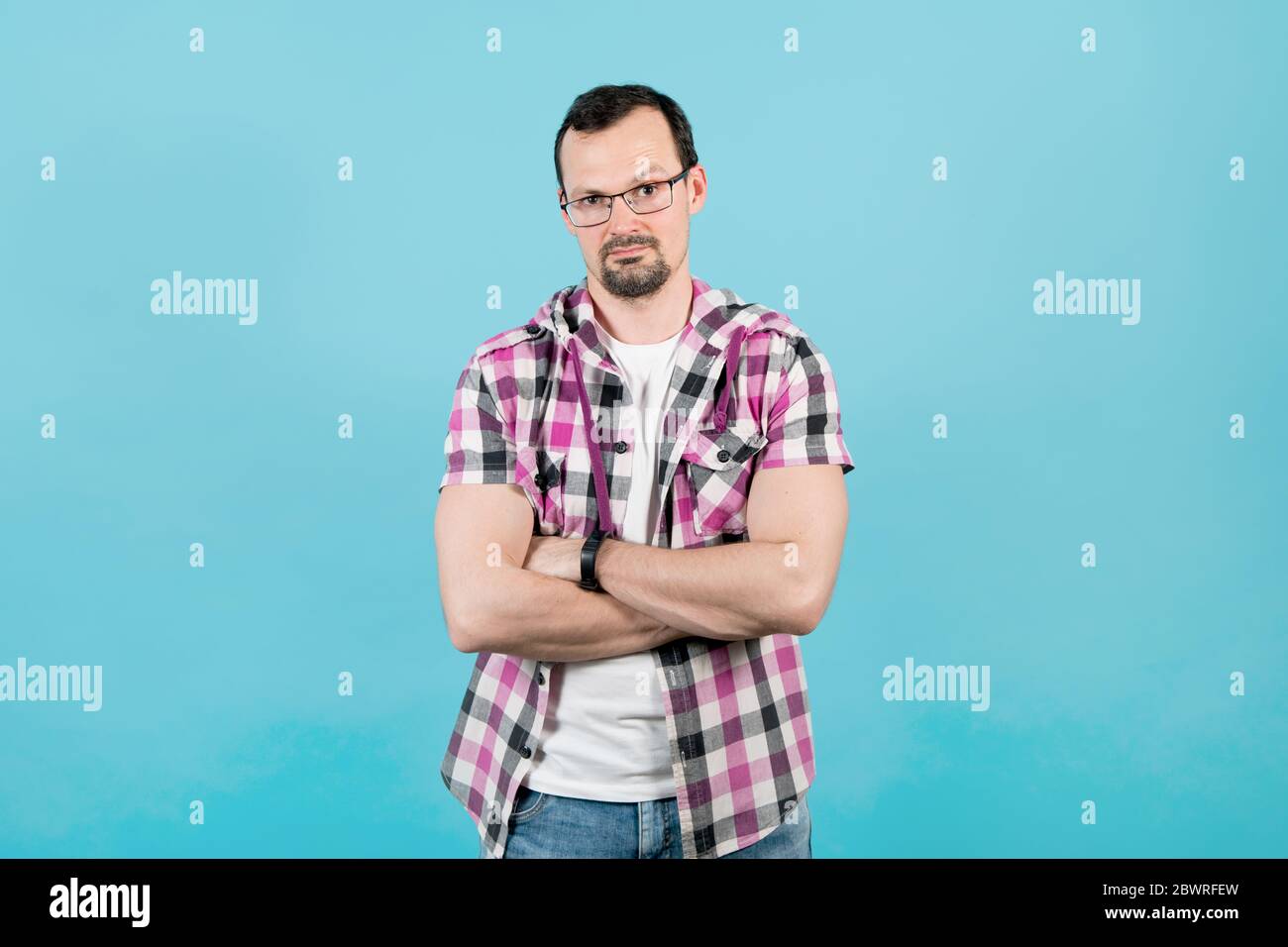 Ein junger Mann in einer Brille sieht fragend aus, eine Augenbraue hochhebend Stockfoto