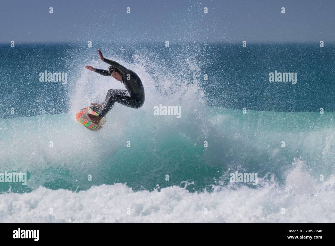 Wilde spektakuläre Action, während ein junger Surfer eine Welle im Fistral in Newquay in Cornwall reitet. Stockfoto