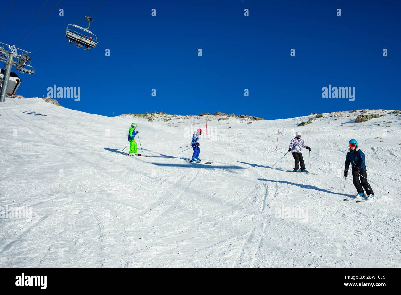 Vier Kinder fahren in der Alpine Piste in Schulbildung gemeinsam eine nach der anderen Stockfoto