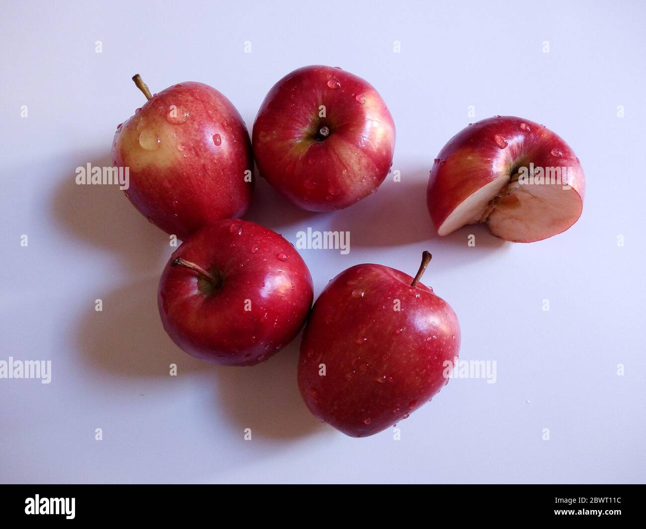 Frische rote Äpfel mit Wassertropfen auf weißem Hintergrund isoliert. Gesundes Lifestyle-Fotokonzept aus dem Blickwinkel. Stockfoto
