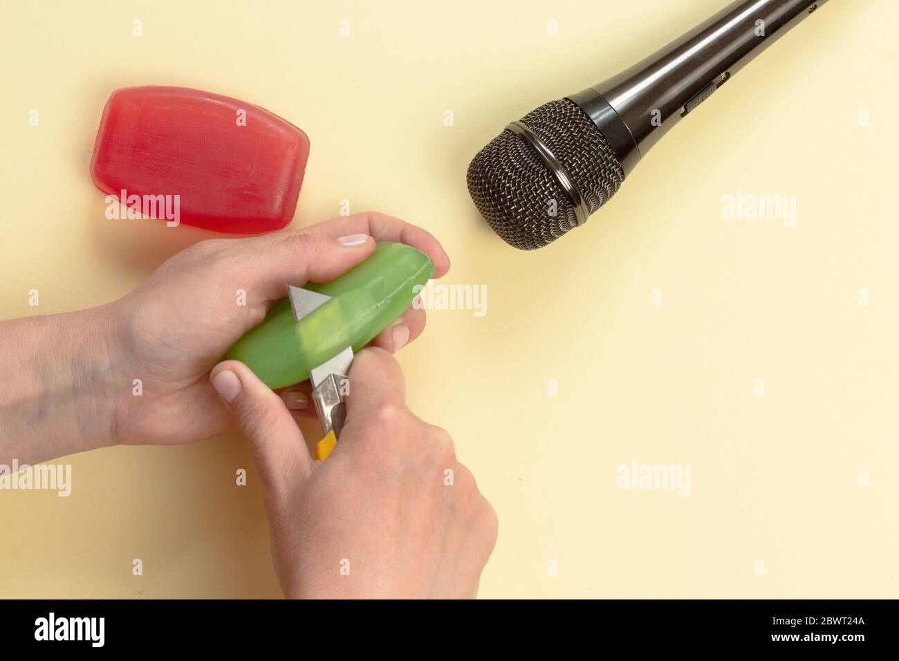 ASMR-Konzept. Spezifische auditive Reizstoffe. Frauenhand schneiden Seife vor dem Mikrofon ab. Draufsicht, flaches Lay. Stockfoto