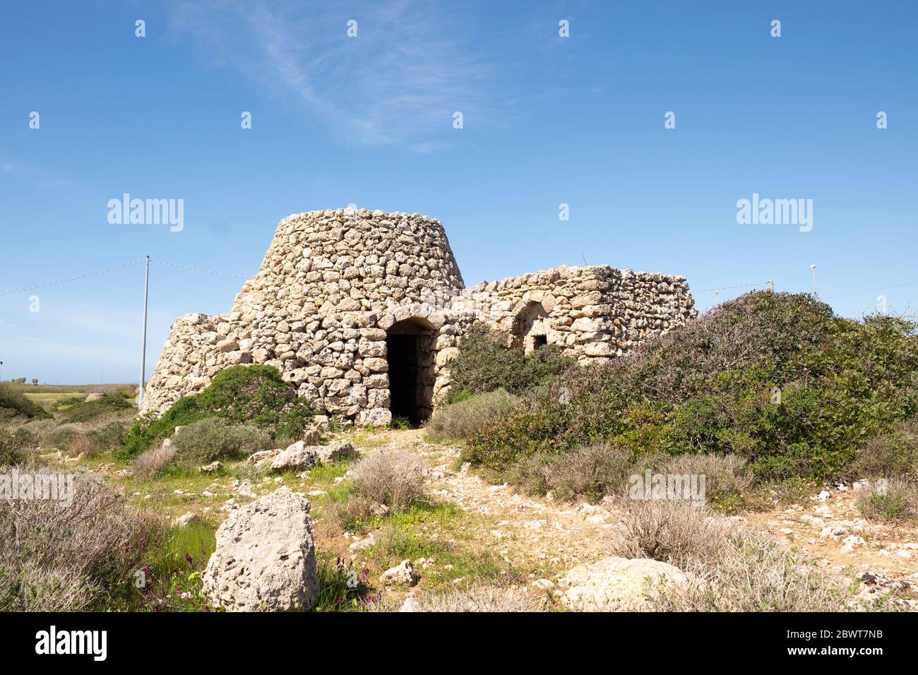 Wir sind in Apulien in Süditalien in Salento unter den wilden Feldern und trocken ist es leicht, kleine Bauernhäuser mit Steinen gebaut zu finden. Stockfoto