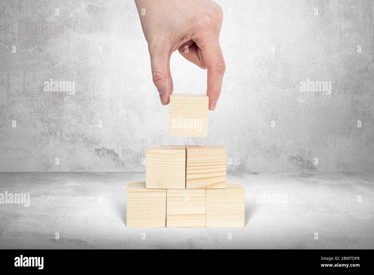 Stapeln von Holzblöcken ohne Inhalt. Geschäftskonzept, inhaltliche Ergänzung. Ein Mann arrangiert leere Holzblöcke übereinander, Kreatin Stockfoto