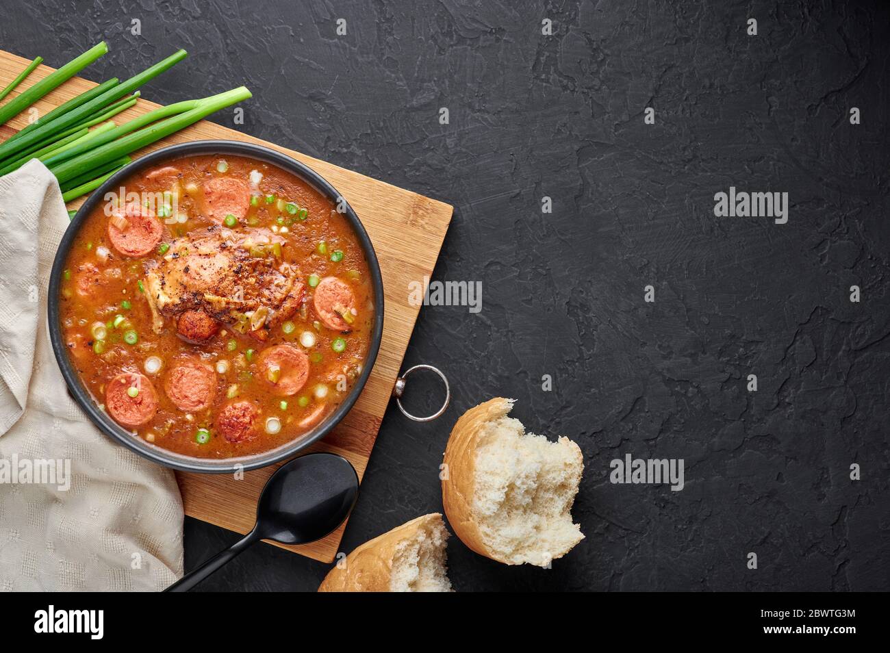 Hähnchen und Wurst Gumbo Suppe in schwarzer Schüssel auf dunklem Schiefer Hintergrund. Gumbo ist louisiana cajun Cuisine Suppe mit Roux. Amerikanische Küche in den USA. Traditionelles E Stockfoto