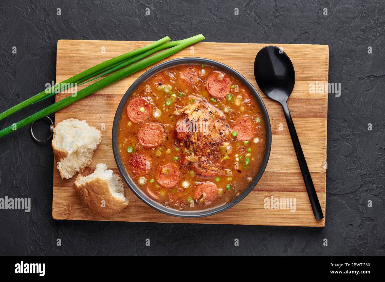 Hähnchen und Wurst Gumbo Suppe in schwarzer Schüssel auf dunklem Schiefer Hintergrund. Gumbo ist louisiana cajun Cuisine Suppe mit Roux. Amerikanische Küche in den USA. Traditionelles E Stockfoto