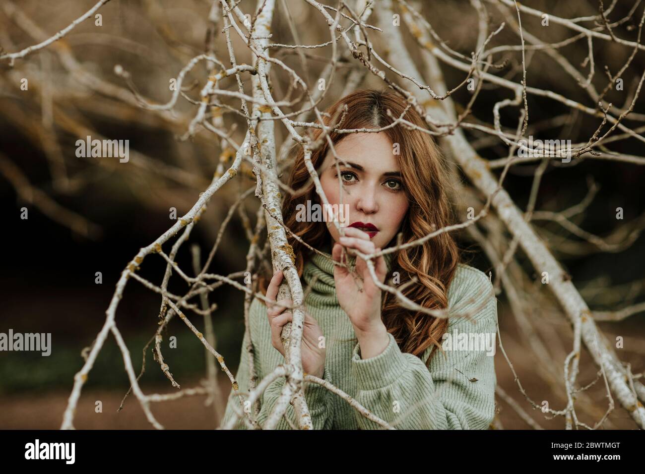 Porträt der modischen Frau zwischen den Zweigen Stockfoto