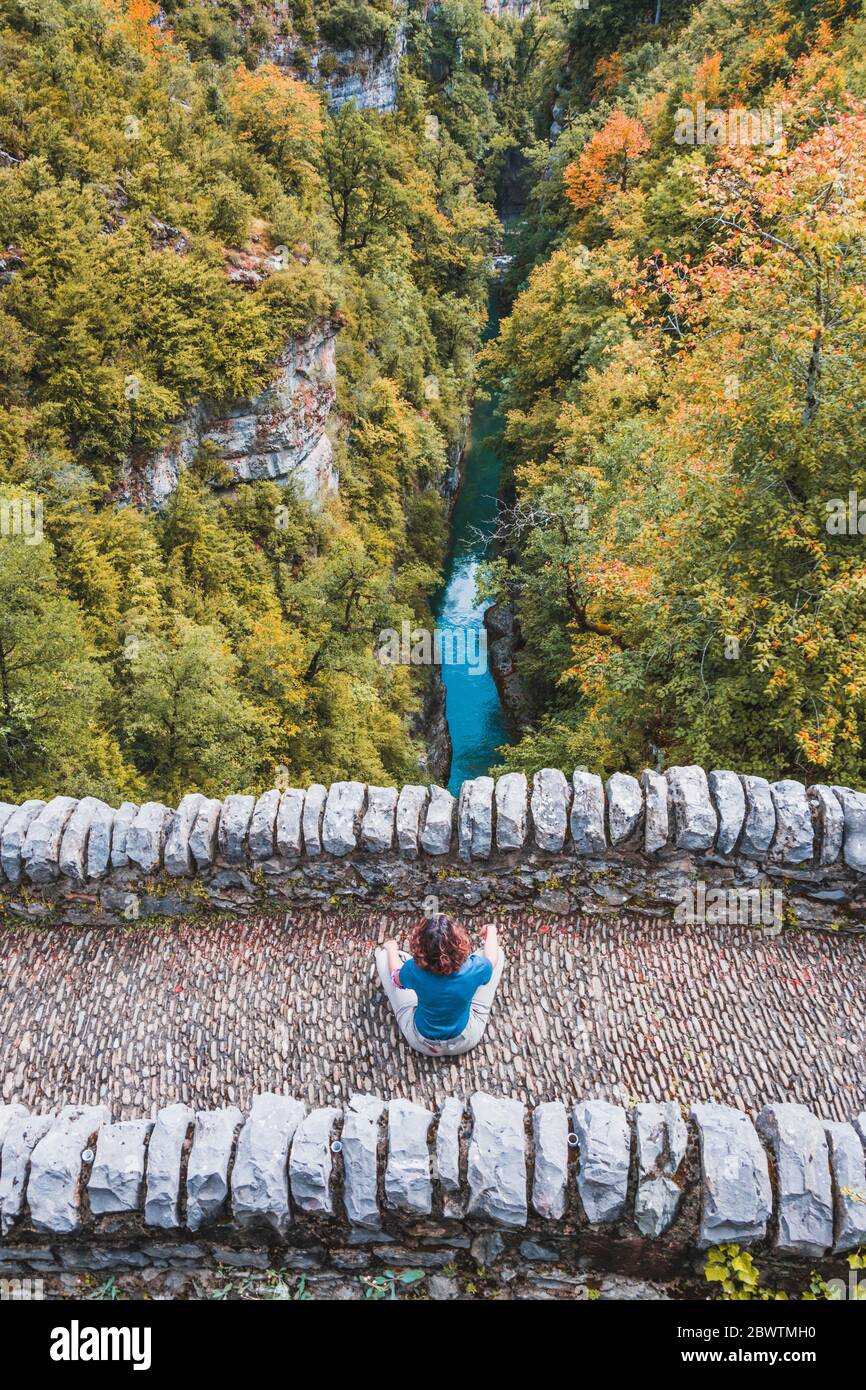 Spanien, Provinz Huesca, Luftaufnahme einer jungen Frau, die auf einer Steinbrücke sitzt Stockfoto