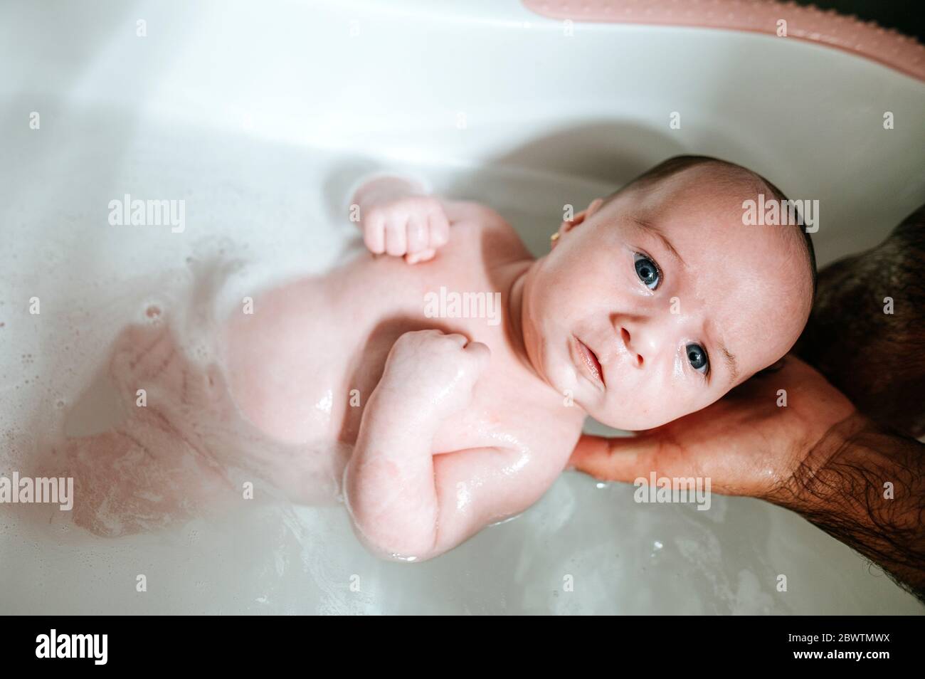 Baby Mädchen Baden, halten von den Händen des Vaters Stockfotografie - Alamy
