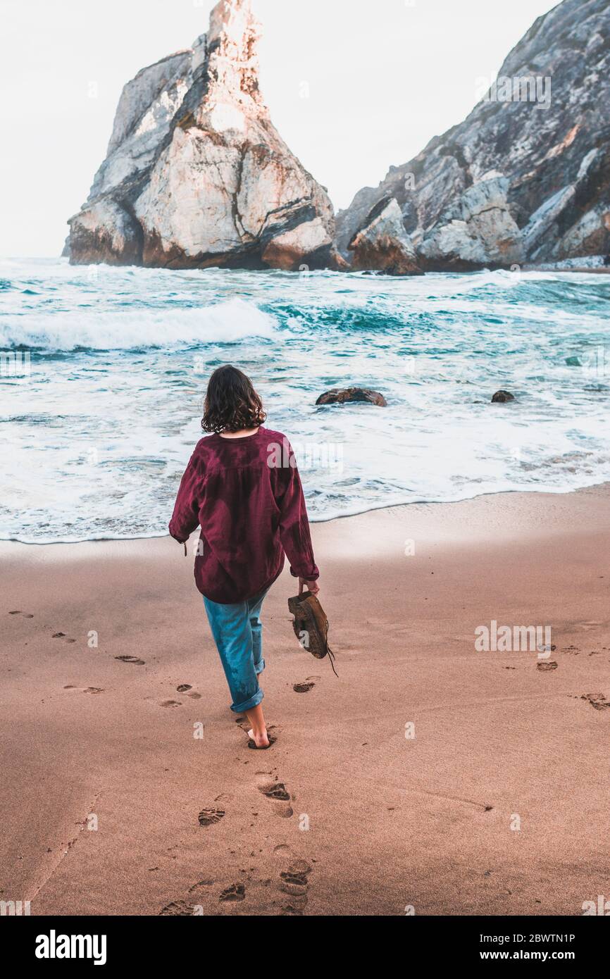 Rückansicht einer jungen Frau, die am Praia da Ursa, Lissabon, Portugal, spazierengeht Stockfoto