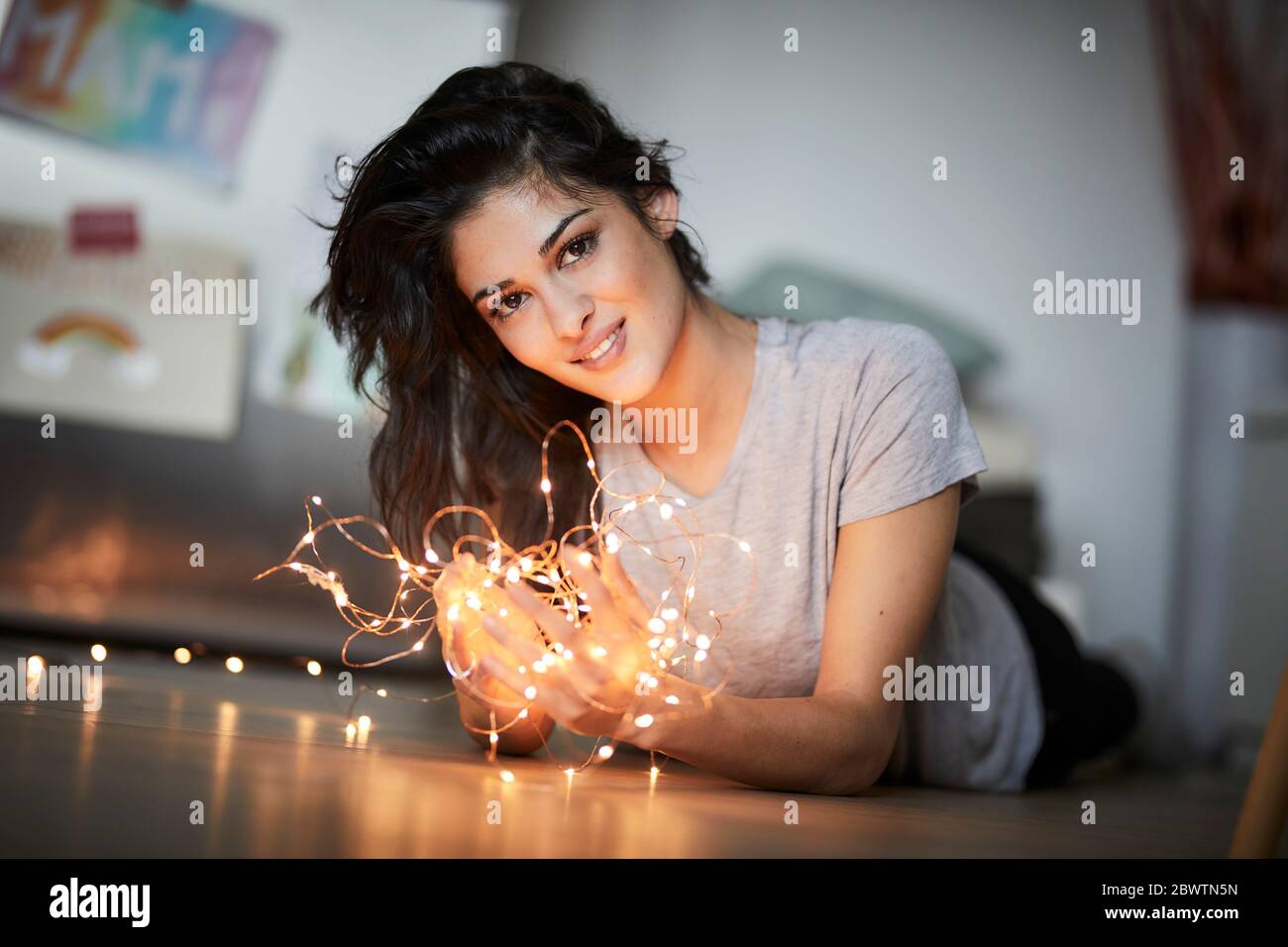 Junge Frau, die auf dem Boden liegt und Lichterketten sieht Stockfoto