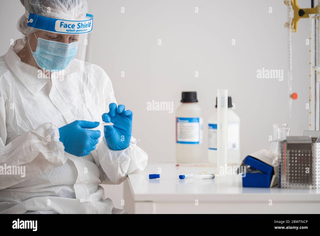 Frau in Schutzkleidung sitzt am Schreibtisch Forschung über Epidemiologie Stockfoto