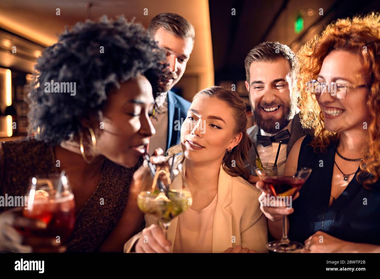 Glückliche Freunde, die in einer Bar mit Cocktails gesellig sind Stockfoto