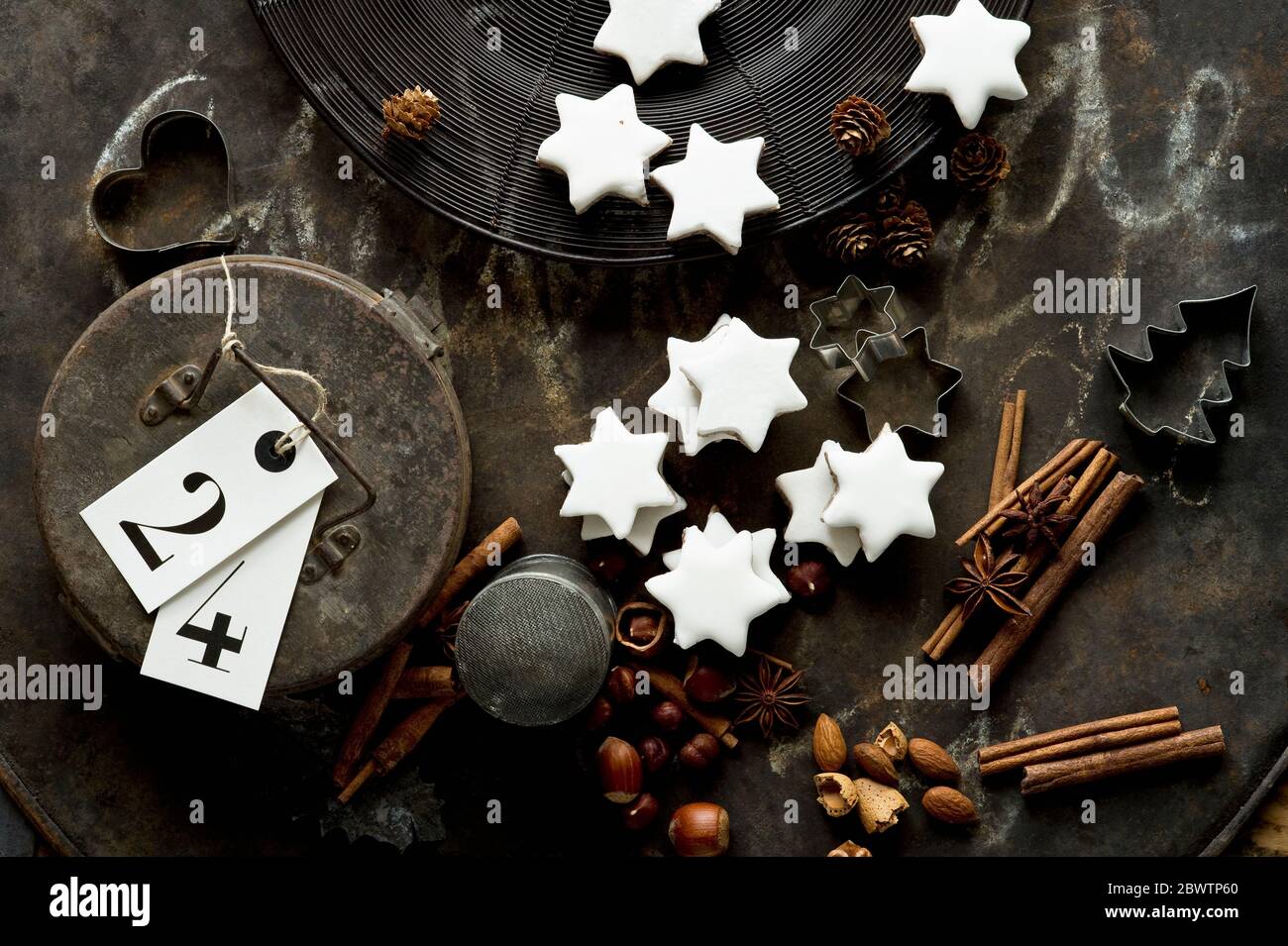 Rustikales Backblech, Zimtstangen, sternförmige Weihnachtskekse, Ausstechformen, Nüsse und Geschenkbox aus Metall Stockfoto