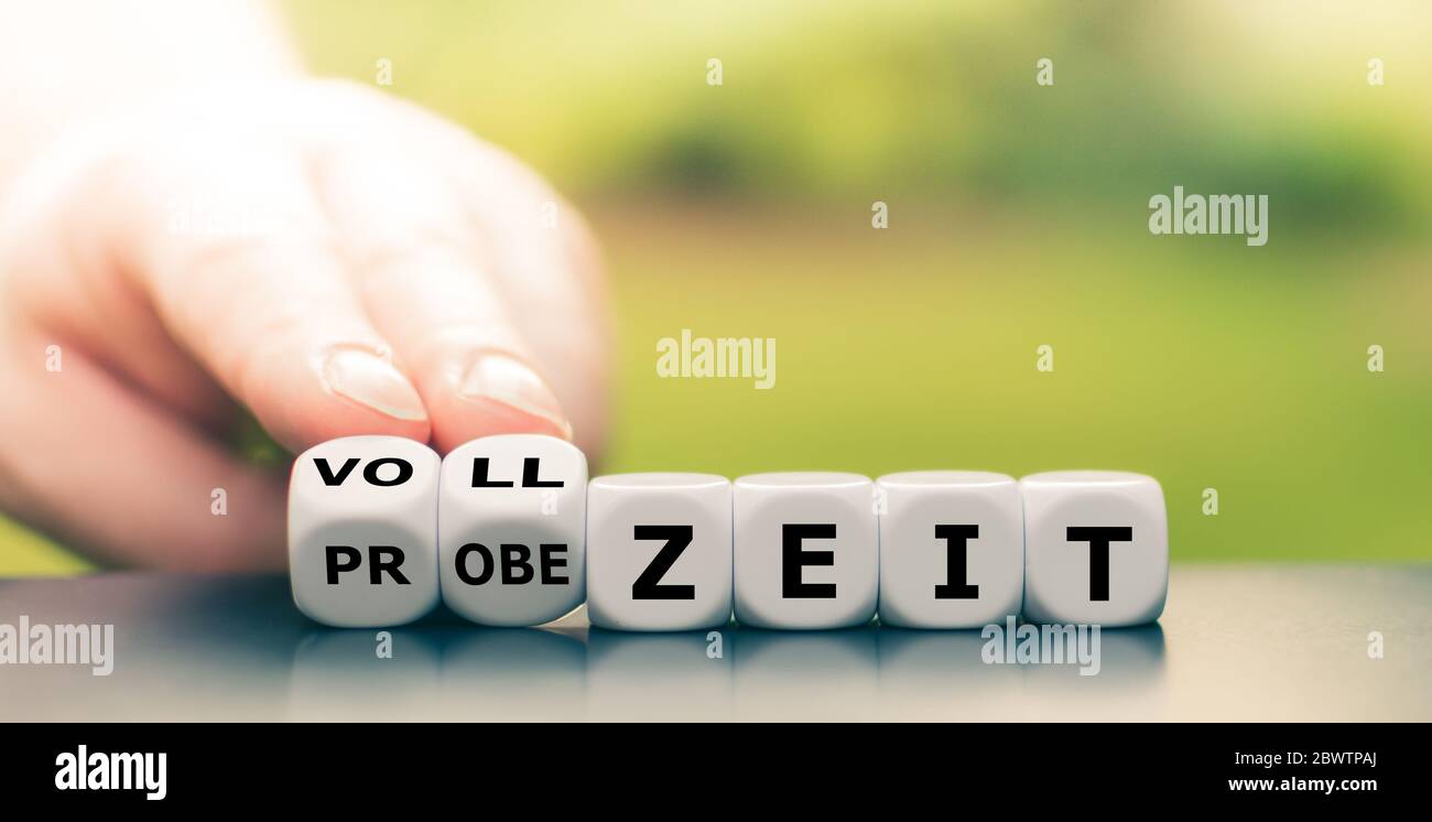 Hand dreht Würfel und ändert den deutschen Ausdruck 'Probezeit' in 'Vollzeit'. Stockfoto