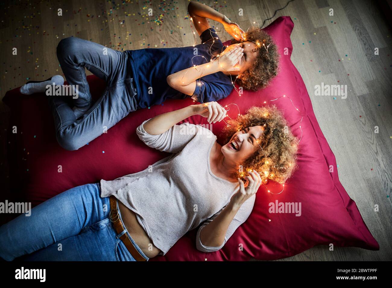 Mutter und Sohn liegen auf dem Boden und spielen mit Lichterketten Stockfoto