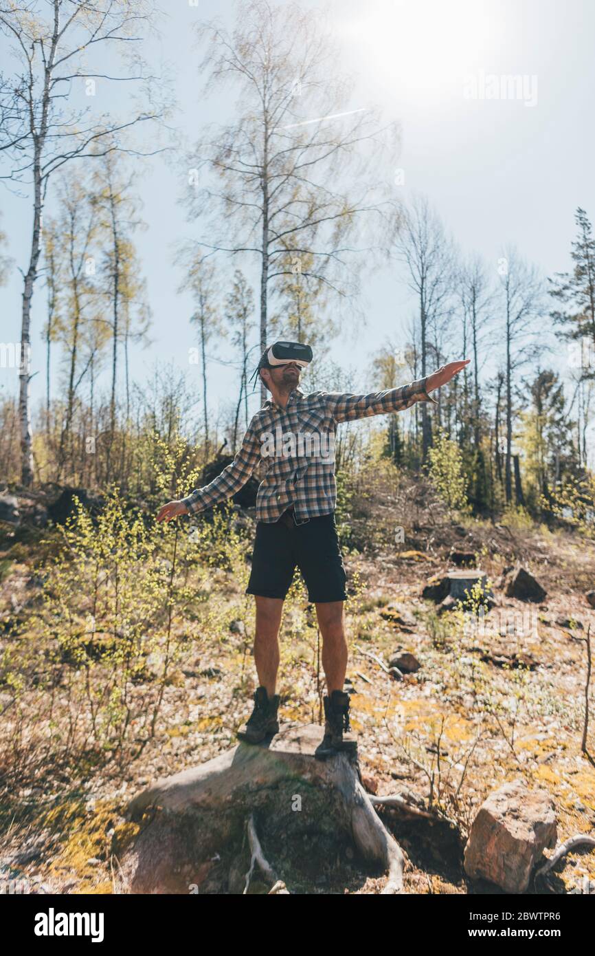 Junger Mann, der mit VR-Brille im Wald Spiele Stockfoto