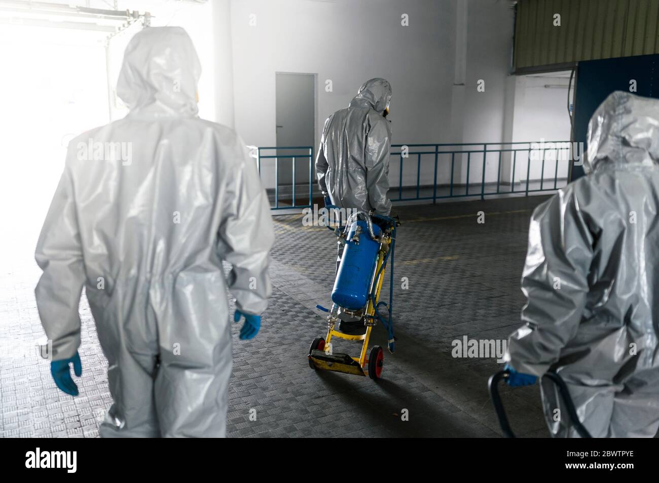 Rückansicht der Arbeiter, die mit der Dekontaminationschemikalien gehen Stockfoto