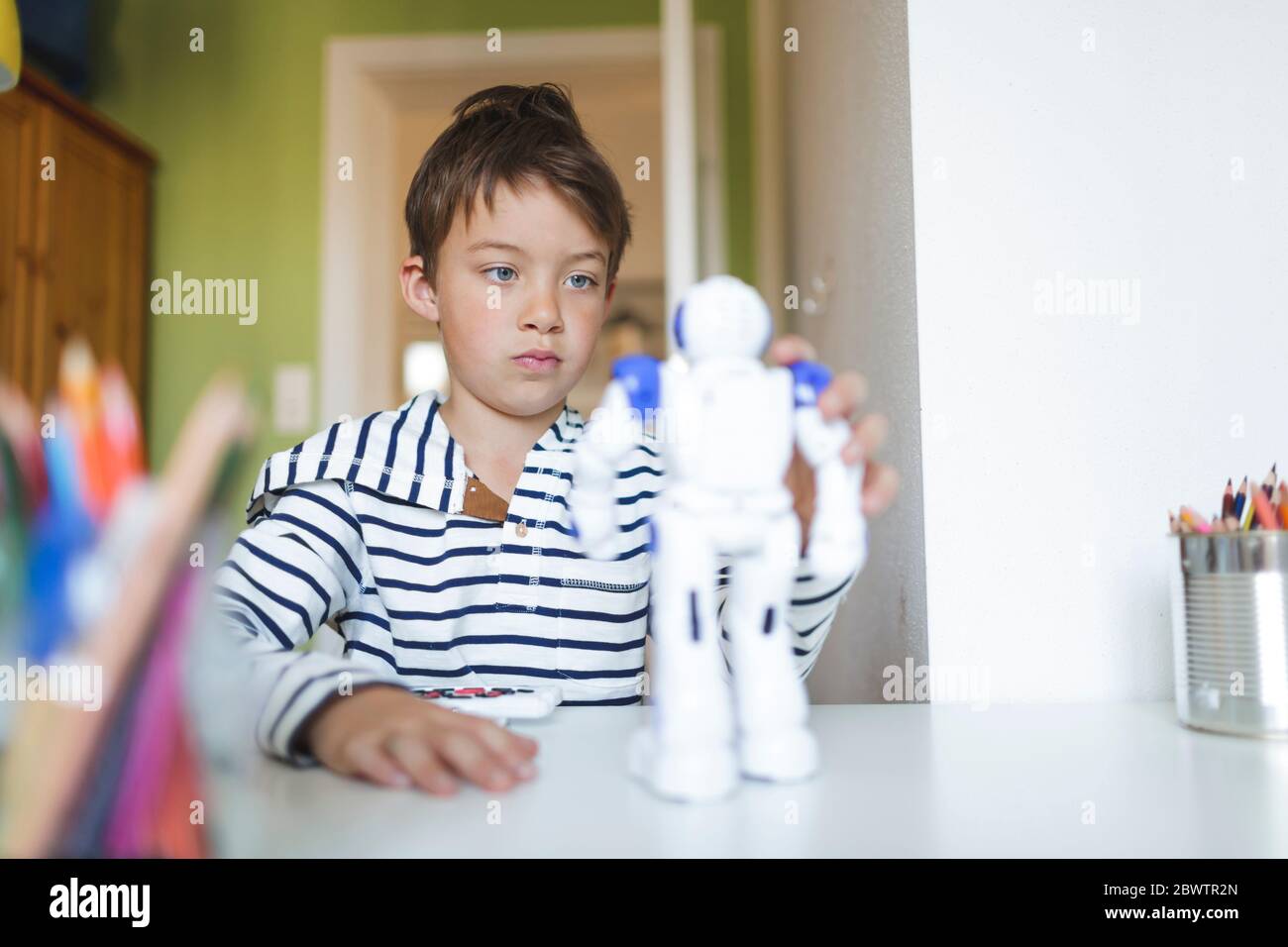 Junge spielt mit seinem ferngesteuerten Spielzeugroboter zu Hause Stockfoto