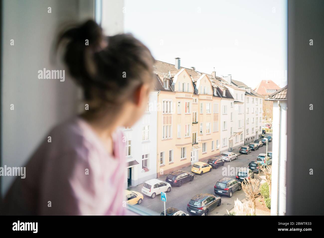 Kleines Mädchen, das aus dem Fenster auf eine Straße schaut Stockfoto