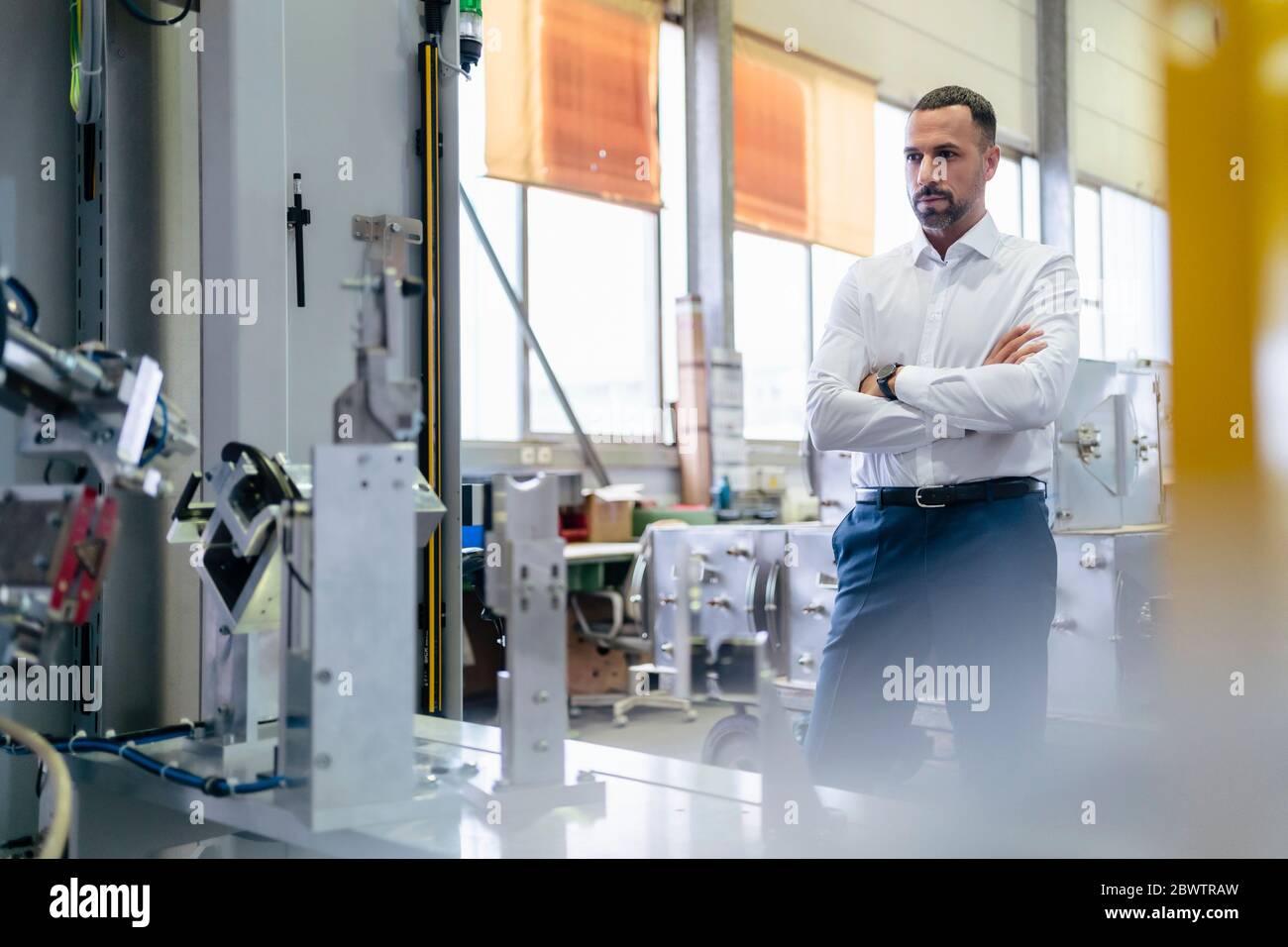 Geschäftsmann, der moderne Maschine in einer Fabrik betrachtet Stockfoto