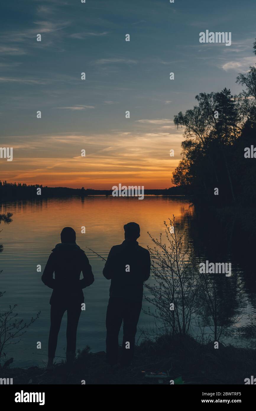 Paar stehen am See, Angeln im See bei Sonnenuntergang Stockfoto