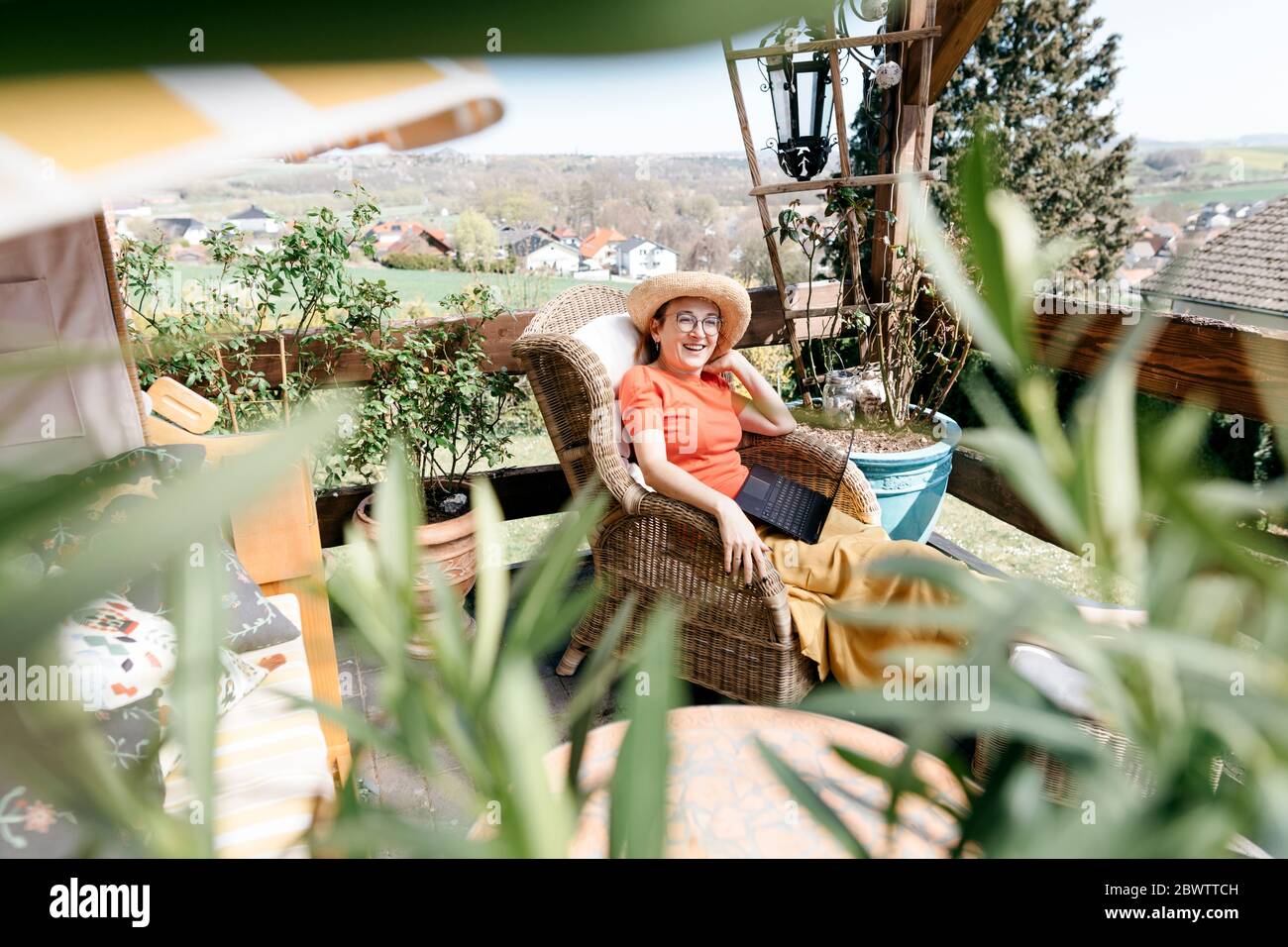Glückliche reife Frau auf der Terrasse mit Laptop auf dem Schoß entspannend Stockfoto