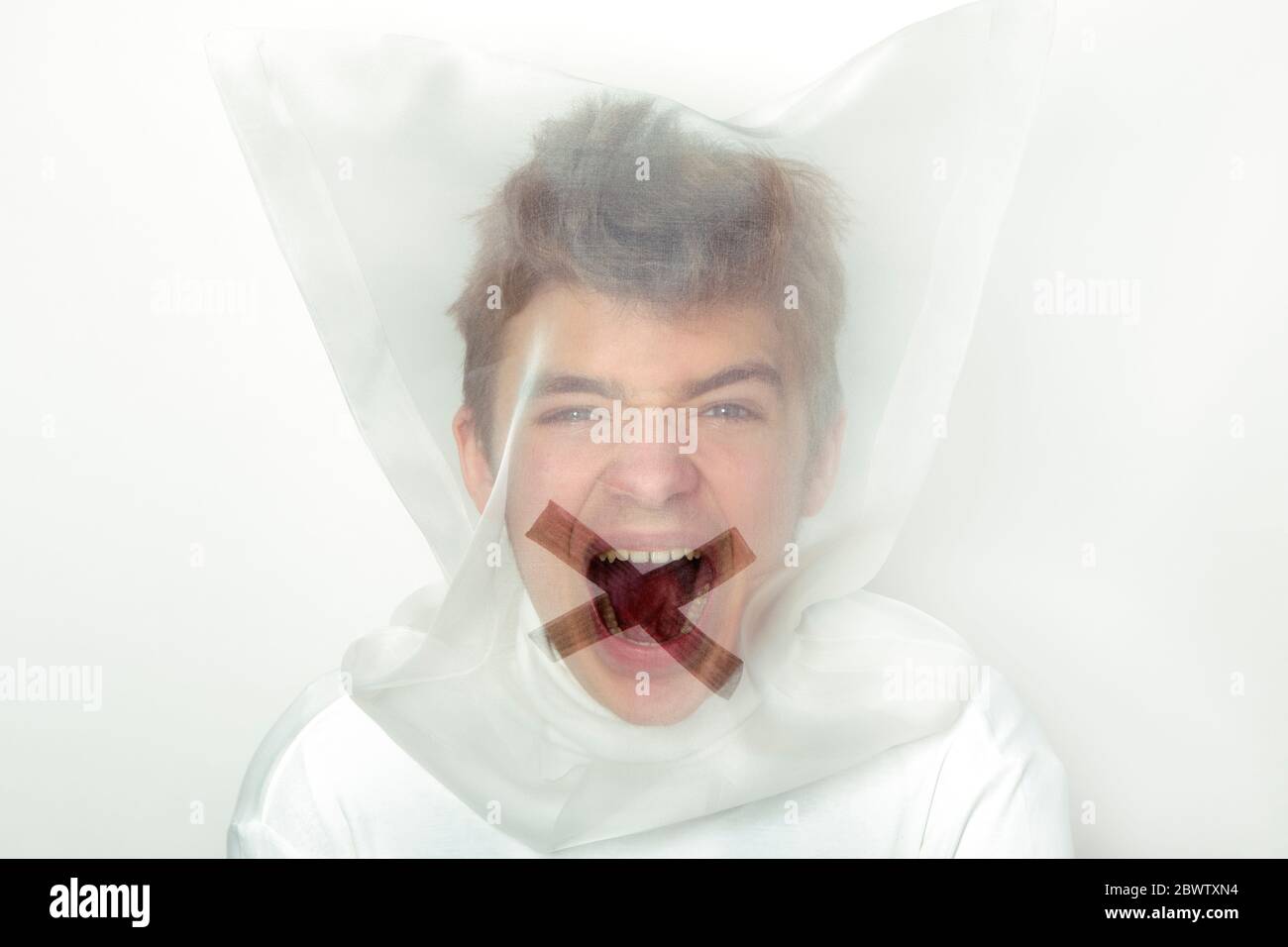 Portrait von schreienden Teenager tragen transparente Maske mit Kreuz auf dem Mund Stockfoto