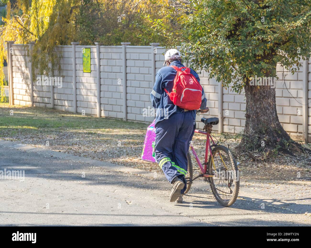 Alberton, Südafrika - nicht identifizierter Radsportler, der sein Fahrrad mit Einkaufen und einem Rucksackbild im horizontalen Format zusammen schiebt Stockfoto