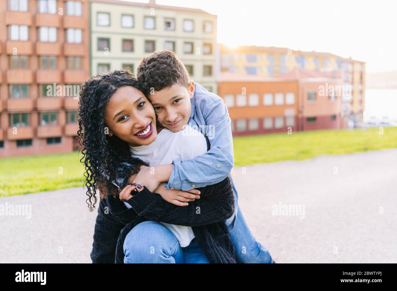 Portrait von glücklichen Jungen umarmt seine Mutter im Freien Stockfoto