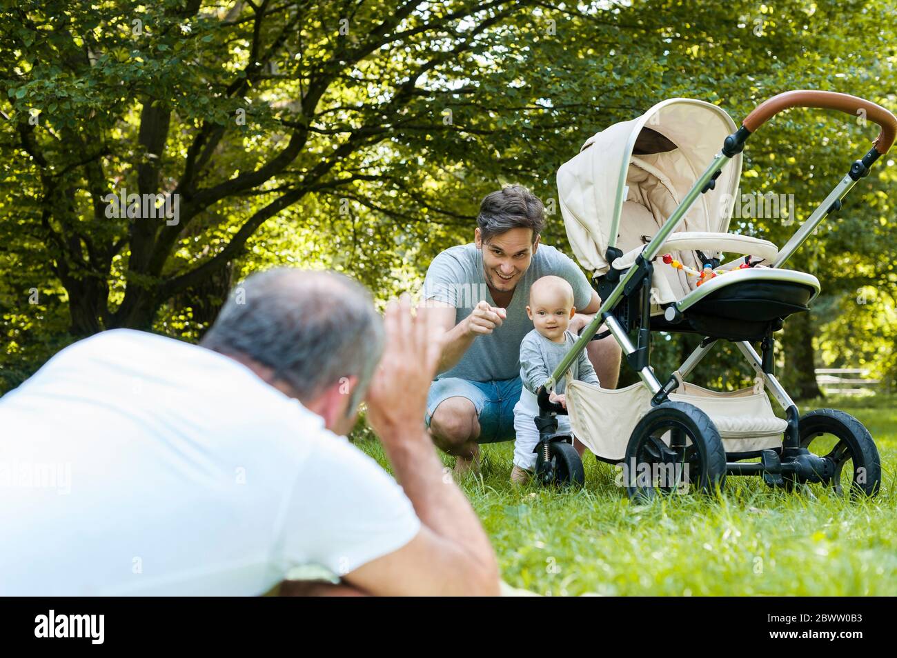 Älterer Mann verbringt Zeit mit seinem erwachsenen Sohn und seiner Enkelin in einem Park Stockfoto