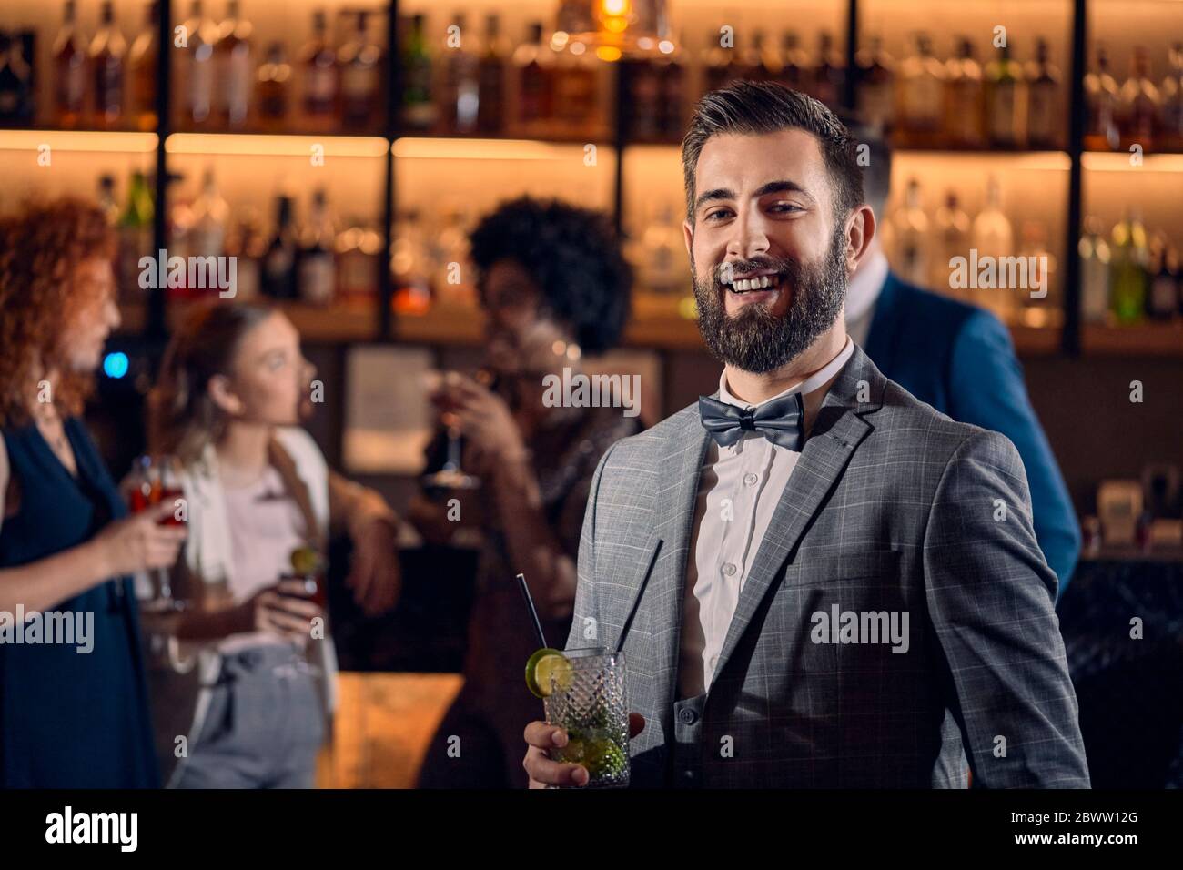 Porträt eines glücklichen jungen Mannes, der einen Cocktail in einer Bar hat Stockfoto