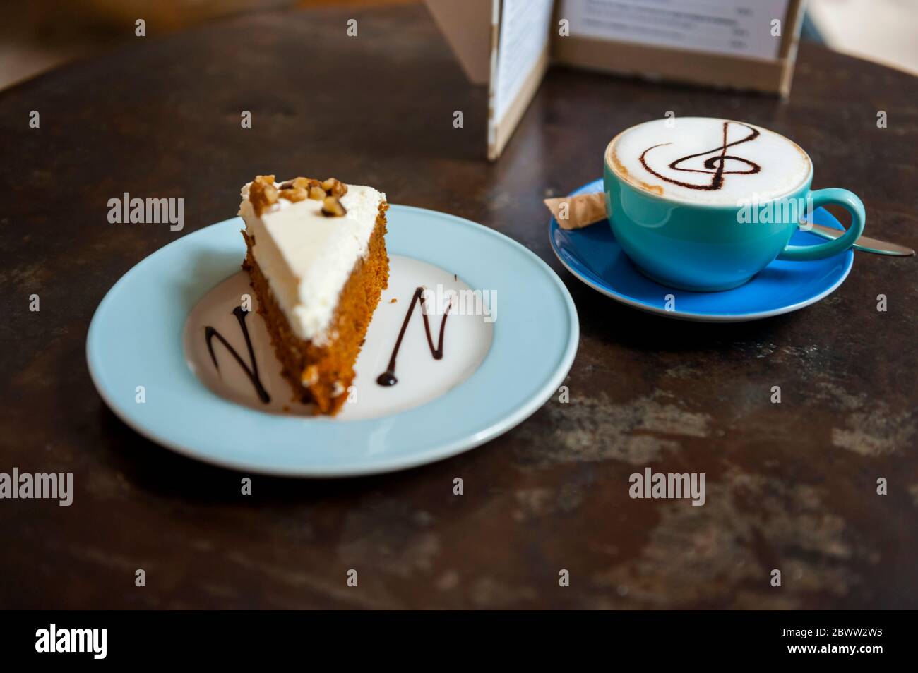 Tasse Cappuchino und Stück Kuchen auf dem Tisch in einem Café Stockfoto