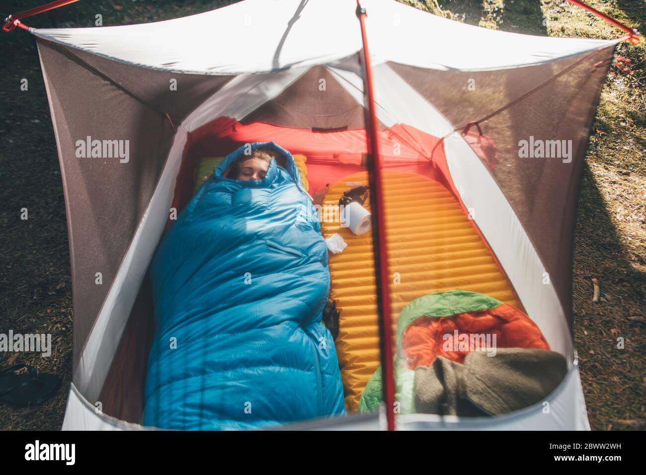 Junge Frau schläft im Schlafsack in einem Zelt Stockfoto