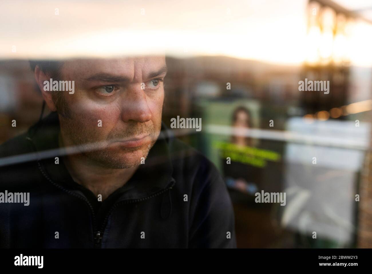 Porträt eines besorgten reifen Mannes, der am Abend aus dem Fenster schaut Stockfoto