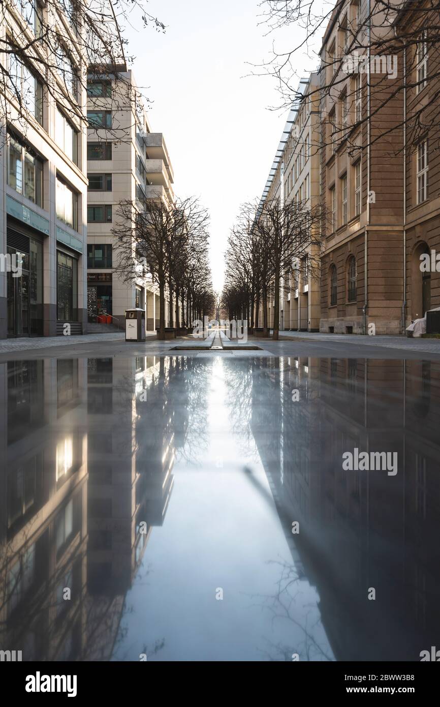 Deutschland, Berlin, Gebäude, die während der COVID-19-Epidemie auf der Oberfläche nasser leerer Straßen reflektiert werden Stockfoto