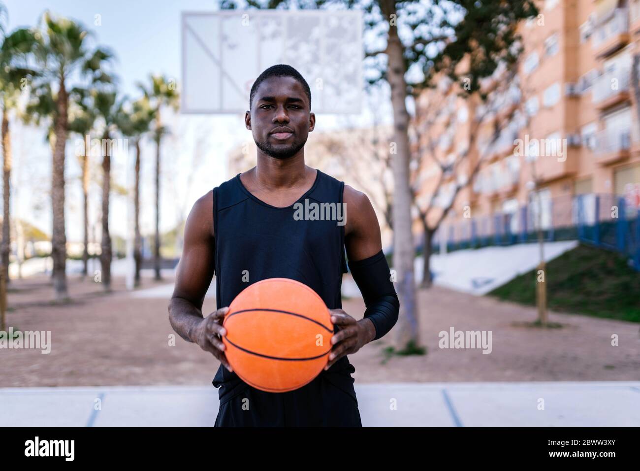 Junger Mann hält Basketball auf dem Basketballplatz Stockfoto