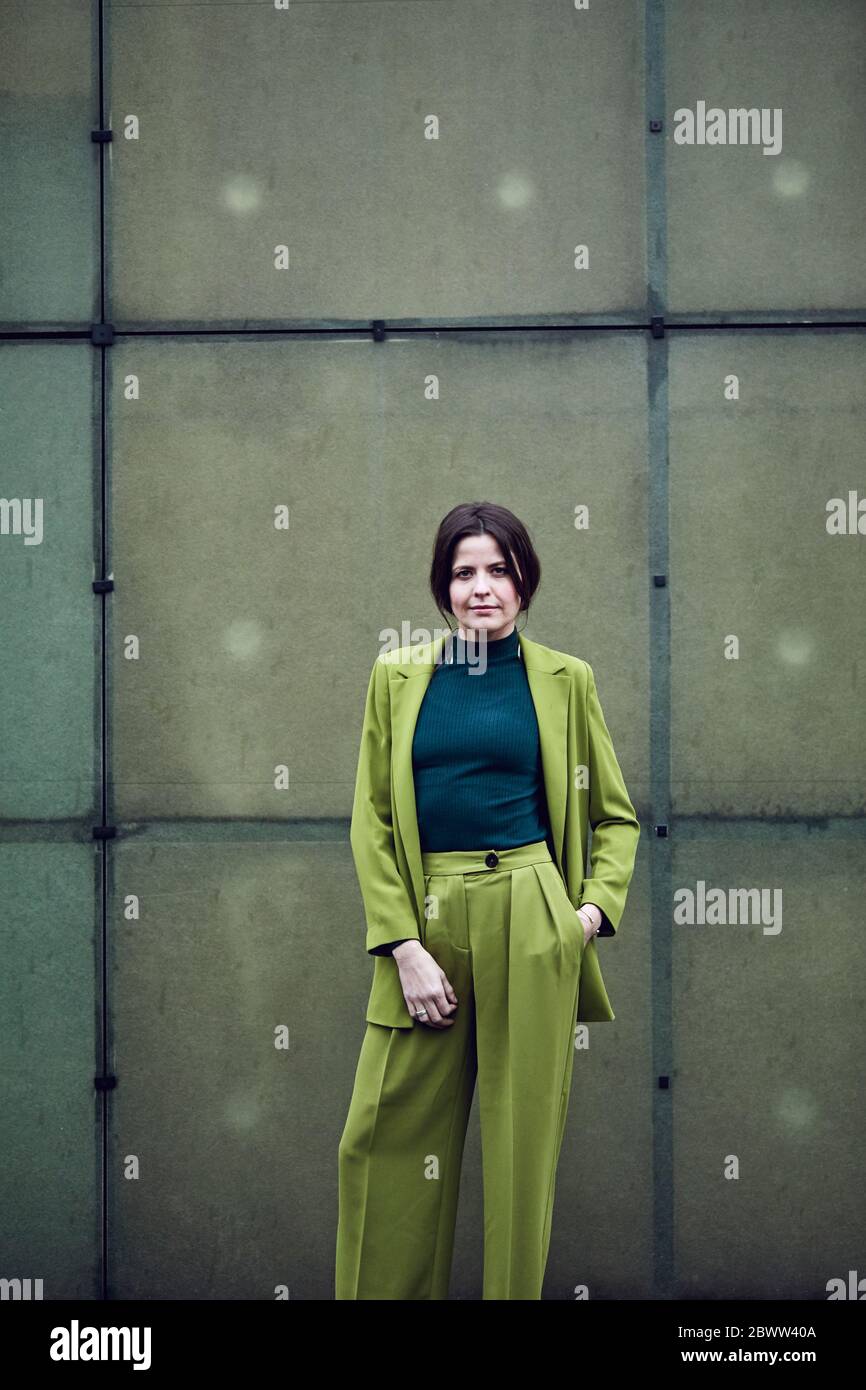 Porträt einer selbstbewussten Geschäftsfrau in einem grünen Anzug an einer Wand stehend Stockfoto