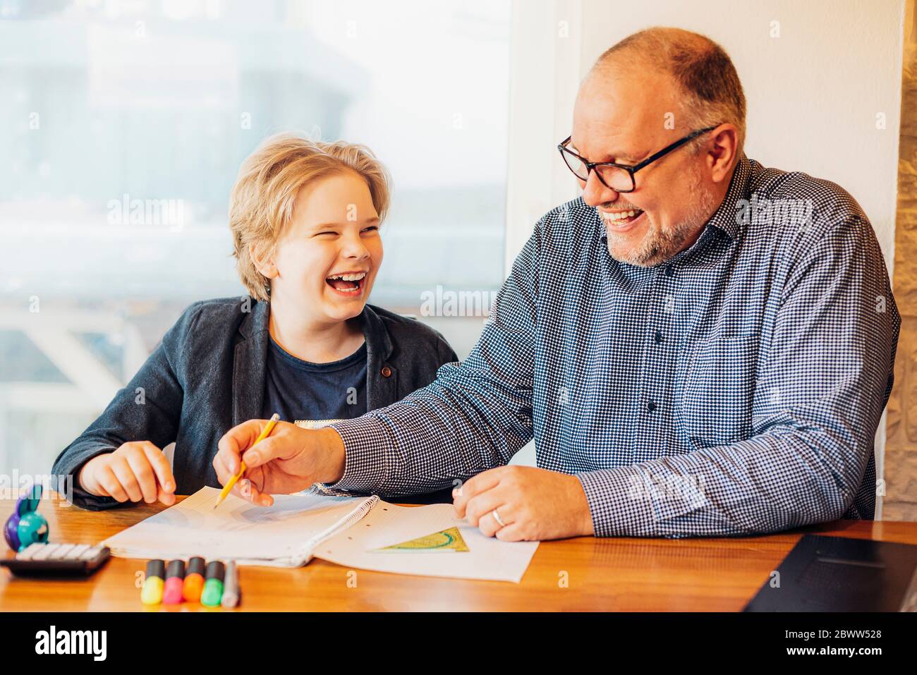 Glücklicher Vater und Sohn machen Hausaufgaben am Schreibtisch Stockfoto