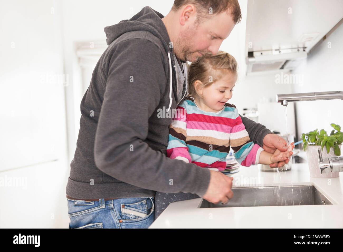 Vater und Tochter waschen sich in der Küche die Hände Stockfoto