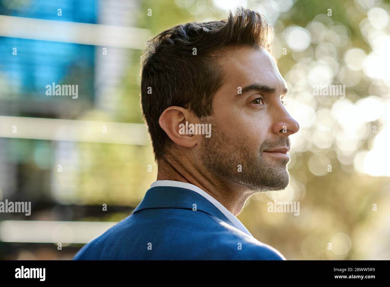 Junger Geschäftsmann schaut sich um, während er in der Stadt steht Stockfoto