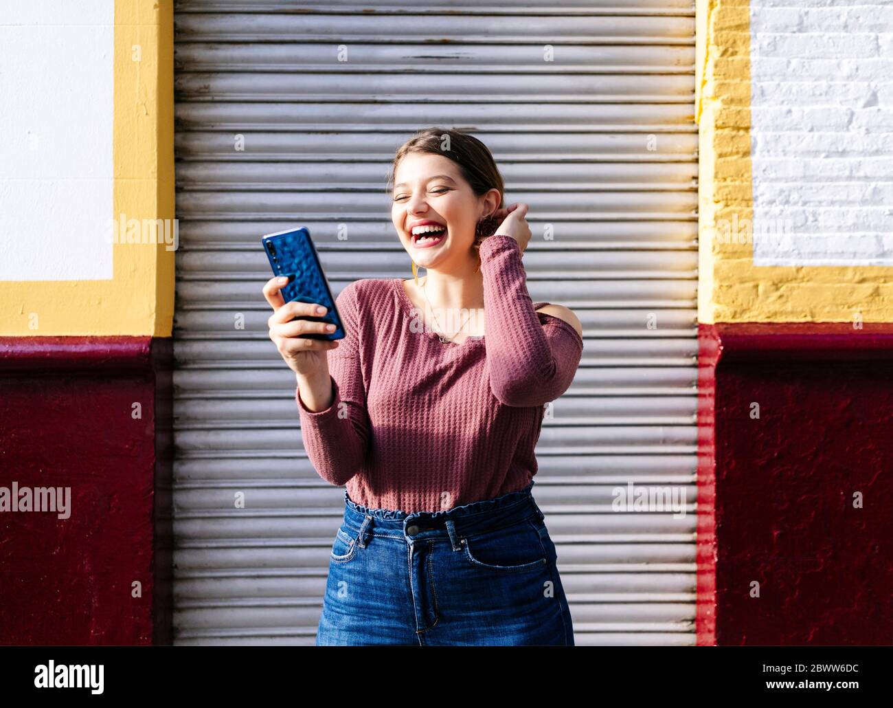 Glückliche Frau mit Smartphone in einem Gebäude in der Stadt Stockfoto